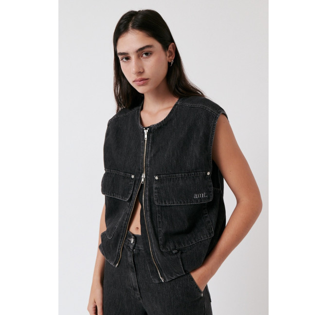 Dunkelhaariges weibliches Model trägt eine Weste aus anthrazit farbenem Denim mit Reißverschluss und zwei großen Fronttaschen